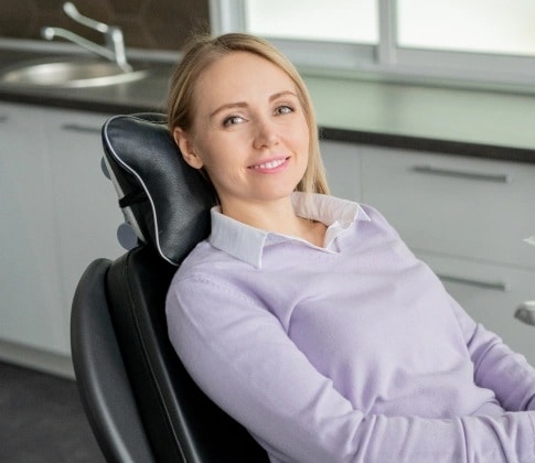 Relaxed female patient sitting comfortably in dental chair during sedation dentistry treatment in Carthage