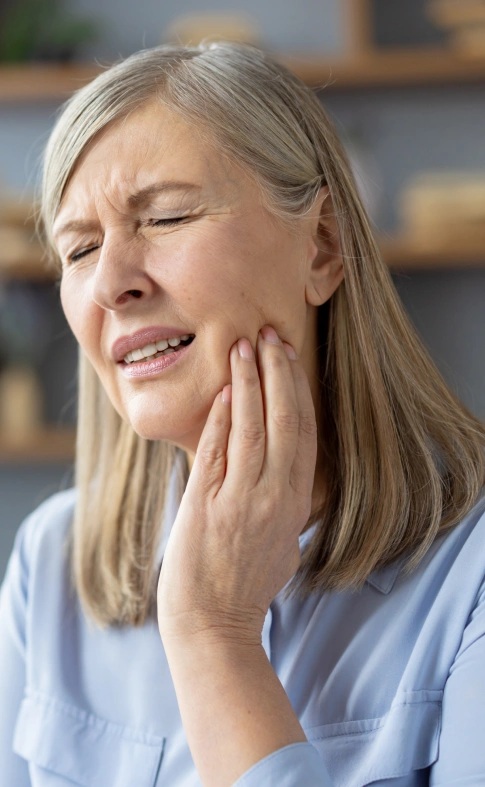 Woman experiencing tooth pain and seeking tooth extraction treatment in Carthage